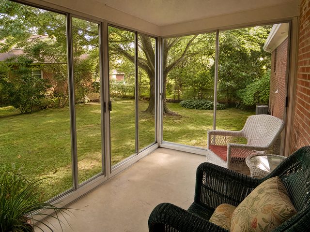 A glass three-season sunroom with light aluminum framing off the back of an NC home