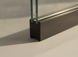 Corner of a dark bronze fiberglass replacement window frame — a slim, matte pultruded profile that holds dark colors